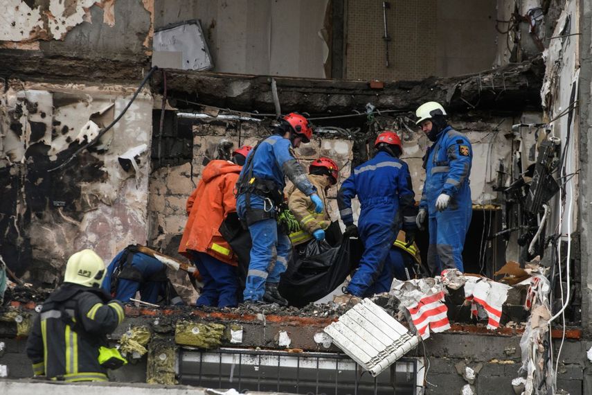 Rescatistas ucranianos transportan el cuerpo de una víctima que quedó atrapada en los escombros de un edificio residencial dañado tras un ataque ruso con drones y misiles en Kiev, el 27 de diciembre de 2025, en medio de la invasión rusa en Ucrania.