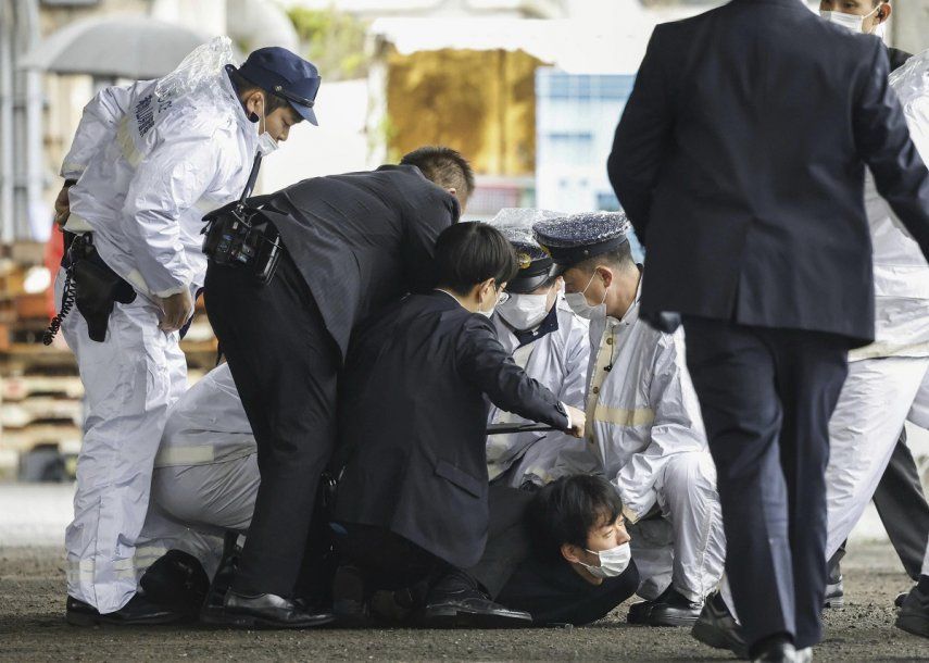 Varios policías sujetan a un hombre tras derribarlo, después de que supuestamente arrojó un objeto explosivo hacia el primer ministro japonés, Fumio Kishida, mientras visitaba el puerto de Saikazaki para un evento de campaña electoral en Wakayama, en el oeste de Japón, el sábado 15 de abril de 2023. Kishida fue evacuado ileso, dijeron las autoridades.&nbsp;