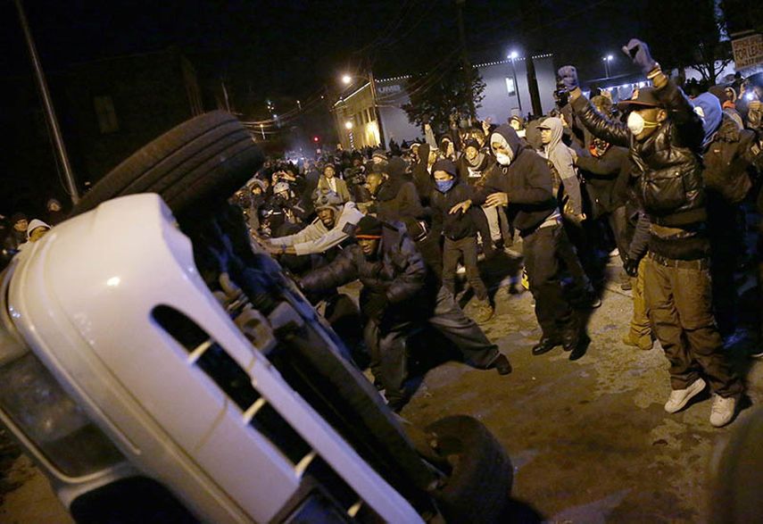 Manifestantes voltean el martes por la noche un vehículo policial en Ferguson. AP