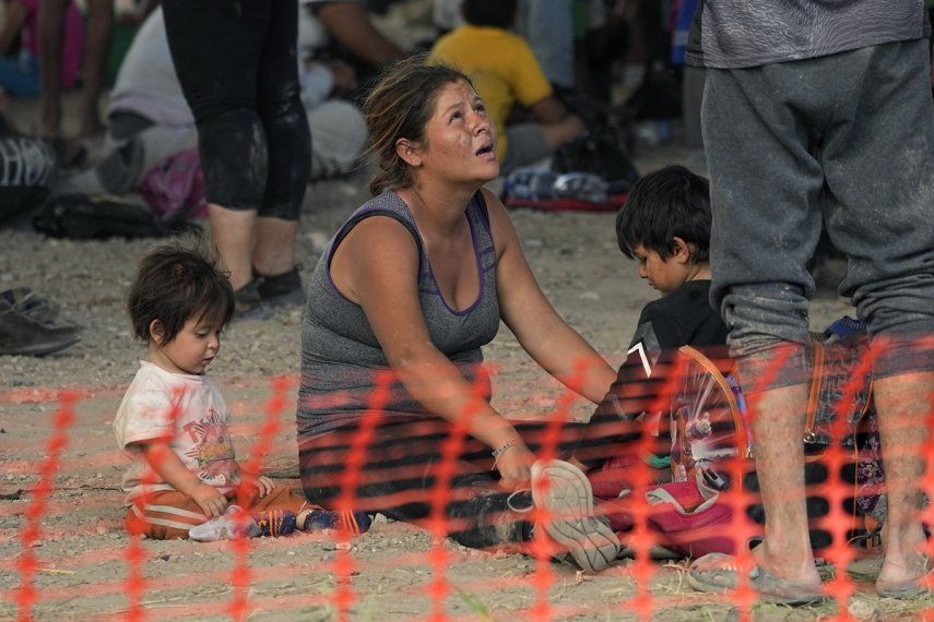 Migrantes que cruzaron desde México a Estados Unidos esperan para subir a un autobús en una zona de procesamiento improvisada a orillas del Río Bravo, el 21 de septiembre de 2023, en Eagle Pass, Texas. 