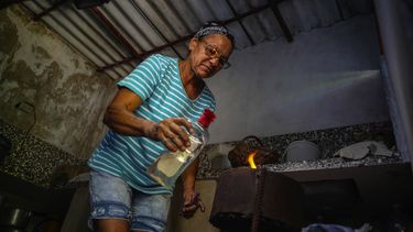 Rosa López enciende un horno a carbón para hervir boniatos y preparar huevos revueltos con tomate para sus nietos en su casa en Mariel, Cuba.&nbsp;