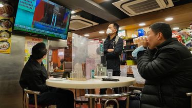 Tres personas observan un programa de televisión que transmite la noticia del ataque ruso a Ucrania, en un restaurante en Hong Kong, el 24 de febrero de 2022.&nbsp;