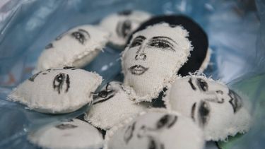 Los rostros de mujeres pintados a mano decoran unas almohadillas que Erika Martínez convertirá en llaveros, que vende para lograr algo de dinero mientras vive con su hija en las ocupadas oficinas de la Comisión Nacional de Derechos Humanos, que se han convertido en un refugio para víctimas de la violencia de género como ellas, en la Ciudad de México, el 17 de noviembre de 2020.