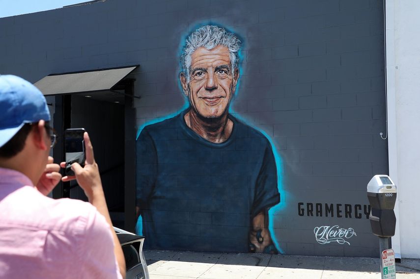Un hombre toma una foto de un mural con la imagen de Anthony Bourdain en una pared del restaurante Gramercy, en Santa Mónica.