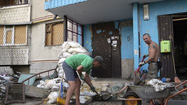Viktor Lazar, a la derecha, limpia la calle ante su apartamento en el distrito de Saltivka tras ataques rusos en Járkiv, Ucrania, el 5 de julio de 2022.&nbsp;