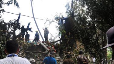 Miembros del Departamento de Bomberos de Cuba inspeccionan el lugar donde se estrelló un avión de Cubana de Aviación este viernes 18 de mayo, en las inmediaciones del Aeropuerto Internacional José Martí de La Habana.