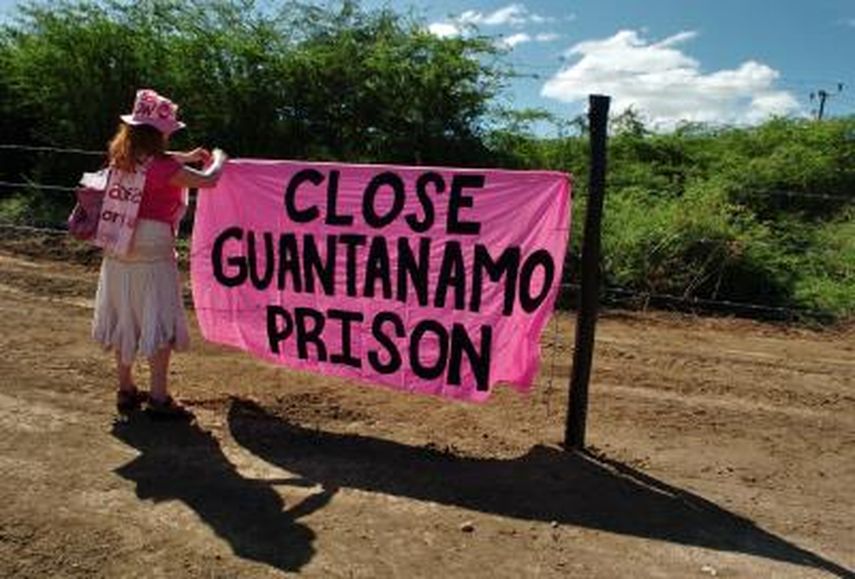 Una pacifista estadounidense coloca un cartel en la cerca que separa el territorio cubano de la Base Naval de EEUU en Guantánamo. (EFE/Archivo)