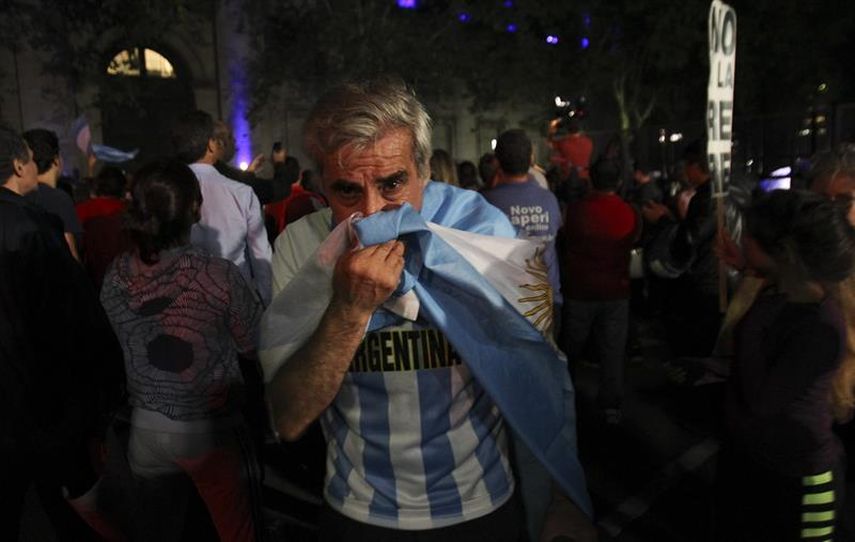 Un grupo de personas se protege tras recibir gases lacrimógenos por parte de la policía este lunes, 19 de enero de 2015, en los alrededores de la Plaza de Mayo de Buenos Aires, frente a la Casa Rosada, durante una protesta por la muerte del fiscal Albe