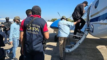 Un agente de la DEA custodia al presunto narcotraficante hondureño José Rafael Sosa, alias ‘Chafala’, mientras sube a un avión en la base aérea de Palmerola en la ciudad de Comayagua, a 50 km al norte de Tegucigalpa, el 4 de marzo de 2025.&nbsp;