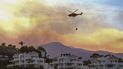 Un helicóptero vierte agua sobre un incendio forestal que avanza cerca de algunas residencias el jueves 9 de junio de 2022, en Marbella, Málaga. 