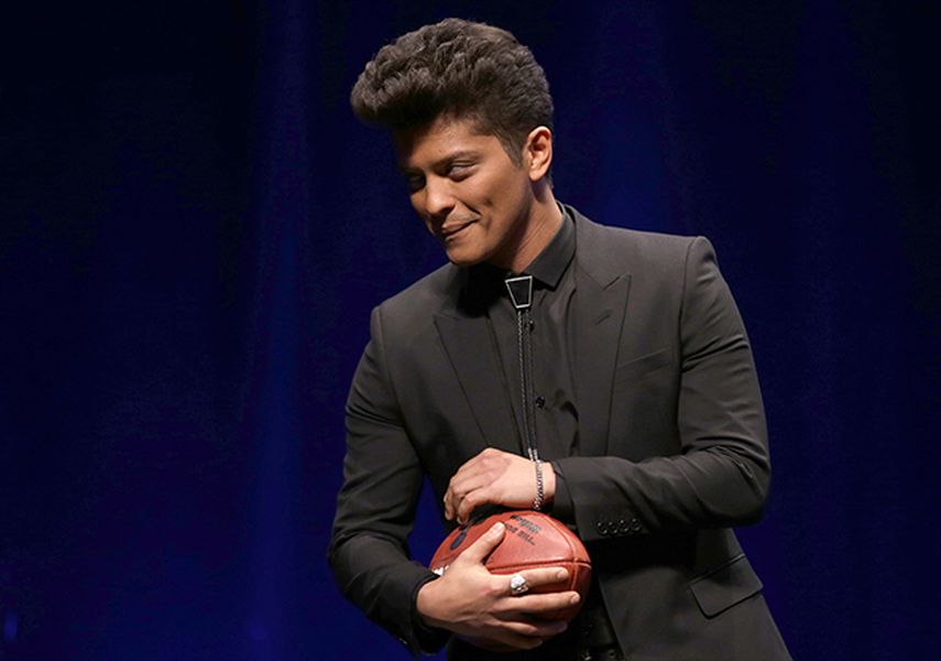 Bruno Mars, quien encabezará el espectáculo de medio tiempo en el Super Bowl XLVIII de la NFL, toma el balón del partido durante una conferencia de prensa. (AP)
