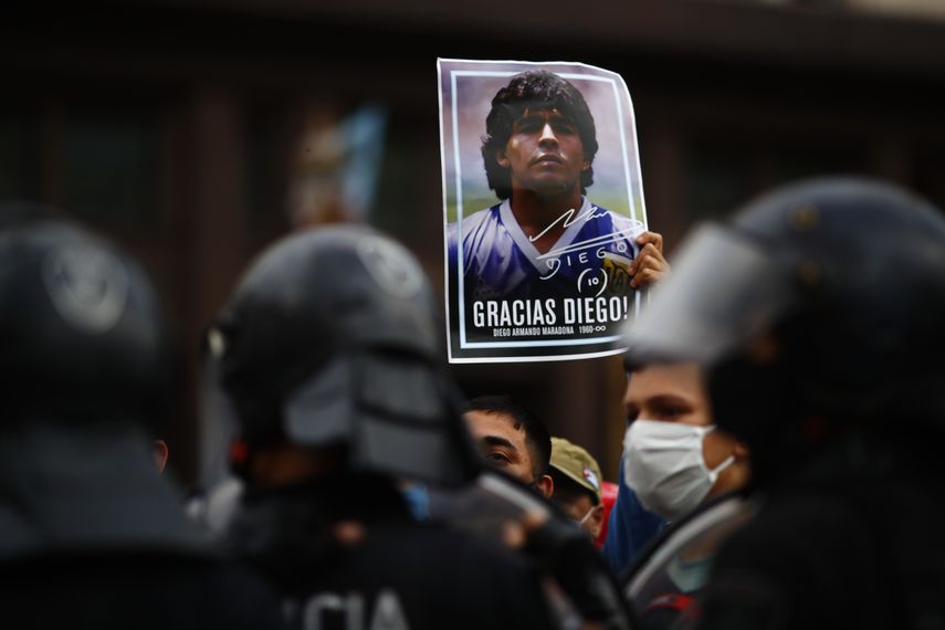 Un hombre sostiene un póster con la cara de Diego Maradona mientras espera en el exterior de la Casa Rosada para acceder a la capilla ardiente, en Buenos Aires, Argentina, el 26 de noviembre de 2020.
