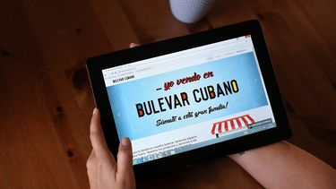 Una joven posa mostrando en una tableta la página de Bulevar Cubano.