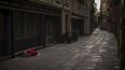En esta imagen del domingo 22 de marzo de 2020, un hombre cubierto por una manta duerme en una calle vacía de Barcelona, España. 