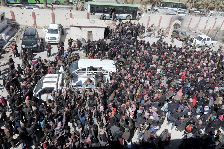 Cientos de civiles esperan a autobuses que los transporten a centros improvisados cercanos, en el área de Housh Nasri, a las afueras de Damasco (Siria).