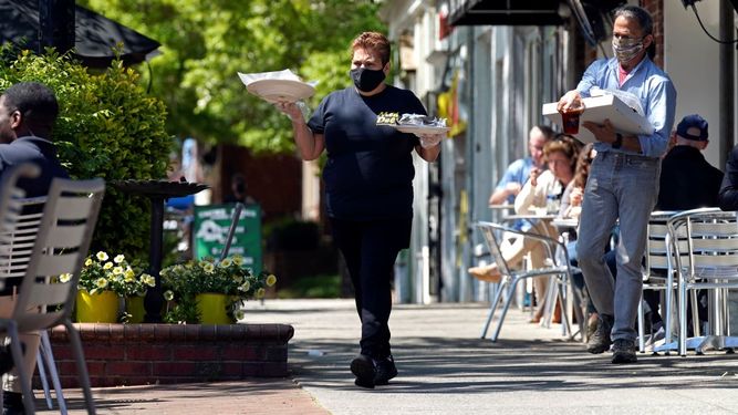 Une empleada de restaurante Mediterranean Deli asiste a los comensales en el área de terraza, en Chapel Hill, Carolina del Norte. &nbsp;