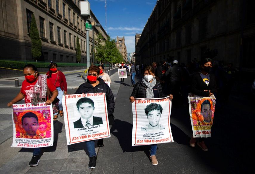 Mujeres con fotografías de sus familiares desaparecidos, que se encuentran entre los 43 estudiantes desaparecidos en Ayotzinapa, México,&nbsp;caminan hacia la puerta del Palacio Nacional donde se reunirán con el presidente Andrés Manuel López Obrador.