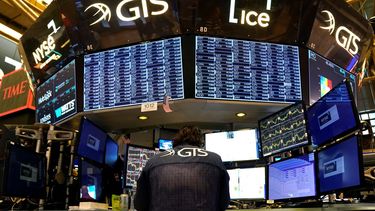 Un agente de la Bolsa de Nueva York frente a pantallas que indican acciones de empresas.