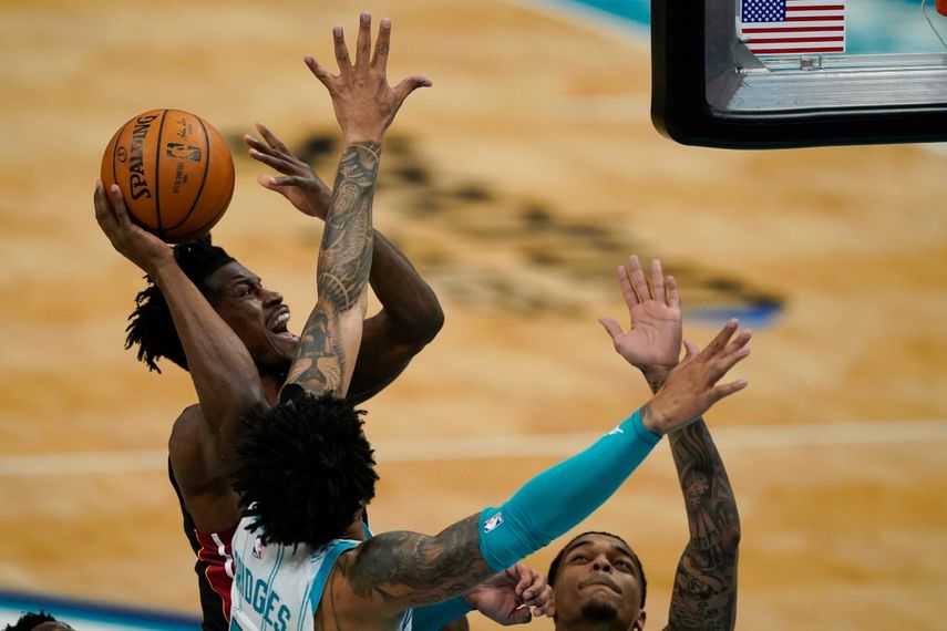 Jimmy Butler, centro, del Heat de Miami, intenta encestar frente a Miles Bridges, de los Hornets de Charlotte