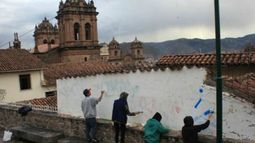 Los extranjeros que pintaron paredes patrimoniales en Cuzco realizando el repintado para tachar graffitis.