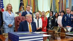 El presidente Donald Trump (sentado) se prepara para firmar una orden ejecutiva que crea la Comisión de Cónyuges Militares en el Despacho Oval de la Casa Blanca, el 3 de agosto de 2026, en Washington, DC.