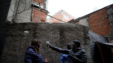 Una voluntaria toma la temperatura de una residente del barrio Fraga el sábado 6 de junio de 2020 durante una cuarentena ordenada por el gobierno para aplanar la curva del coronavirus, en Buenos Aires, Argentina.