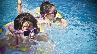 Dos niñas nadan en una piscina en medio del calor del verano.