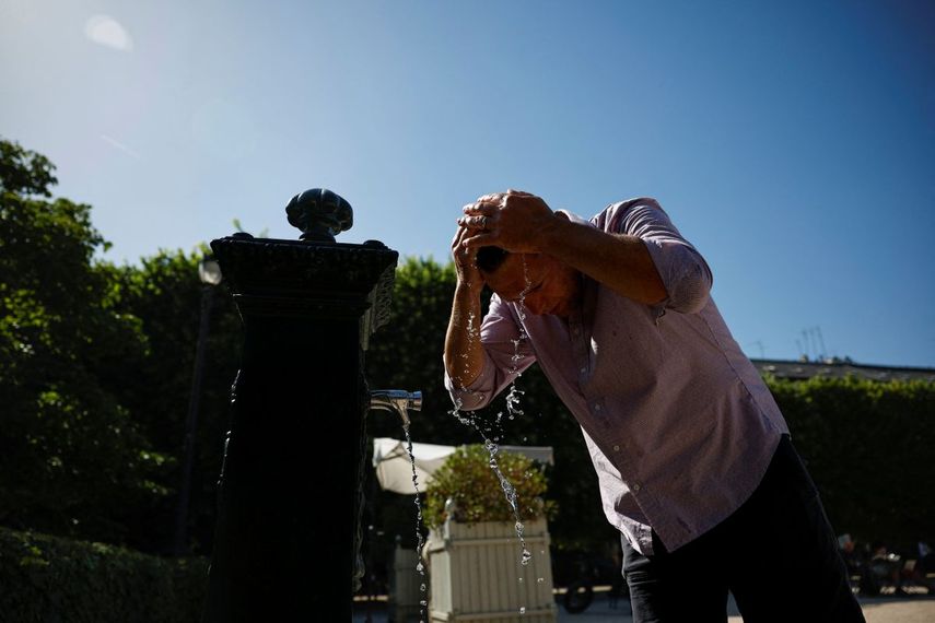Un hombre se refresca echándose agua de una fuente en el cabello en el Jardín del Palais Royal, en el centro de París, el 26 de mayo de 2026, mientras una ola de calor azota Francia.