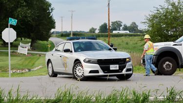 Un empleado del condado de Clinton ayuda a dirigir el tránsito mientras un vehículo de la Patrulla de Caminos del estado de Ohio abandona el sitio donde un hombre armado falleció tras ser baleado por la policía tras irrumpir en una oficina del FBI en Cincinnati, el jueves 11 de agosto de 2022, en Wilmington, Ohio.&nbsp;