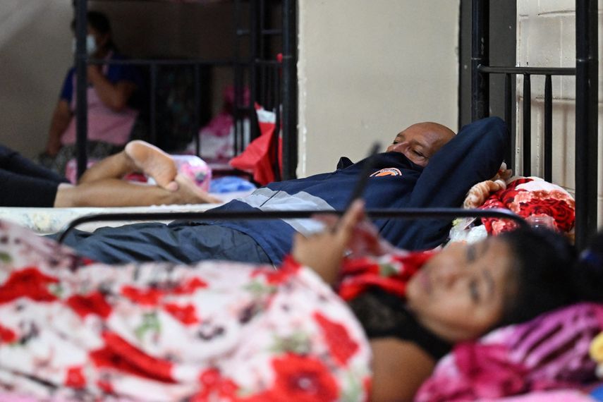Personas que fueron evacuadas de sus hogares por las fuertes lluvias, descansan en un albergue en San Salvador.