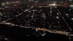 Esta vista aérea muestra la ciudad parcialmente iluminada durante un apagón en Santiago el 25 de febrero de 2025. En plena temporada de verano austral, Chile enfrenta este martes un inusual y masivo apagón debido a una supuesta falla del sistema eléctrico, que obligó a la evacuación del metro de Santiago y sumió en la confusión a la población.&nbsp;
