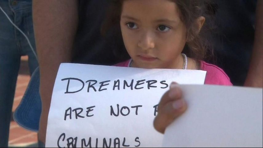 Una niña lleva una hoja de papel que dice que los dreamers no son criminales