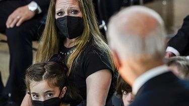 Abigail Evans, de 7 años, y Logan Evans, de 9 (abajo a la derecha, semicubierto), hijos del fallecido policía del Capitolio de Estados Unidos William Billy Evans, observan junto a su madre, Shannon Terranova, al presidente Joe Biden (de espaldas) mientras habla durante un homenaje al oficial Evans en la Rotonda de ese edificio el martes 13 de abril de 2021 en Washington.&nbsp;