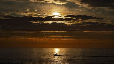 &nbsp;A primera hora de la mañana, un pescador deportivo navega sobre el mar en calma de camino a los bancos de pesca de lubina rayada frente a la costa de Kennebunkport, Maine, el 7 de julio de 2022.&nbsp;