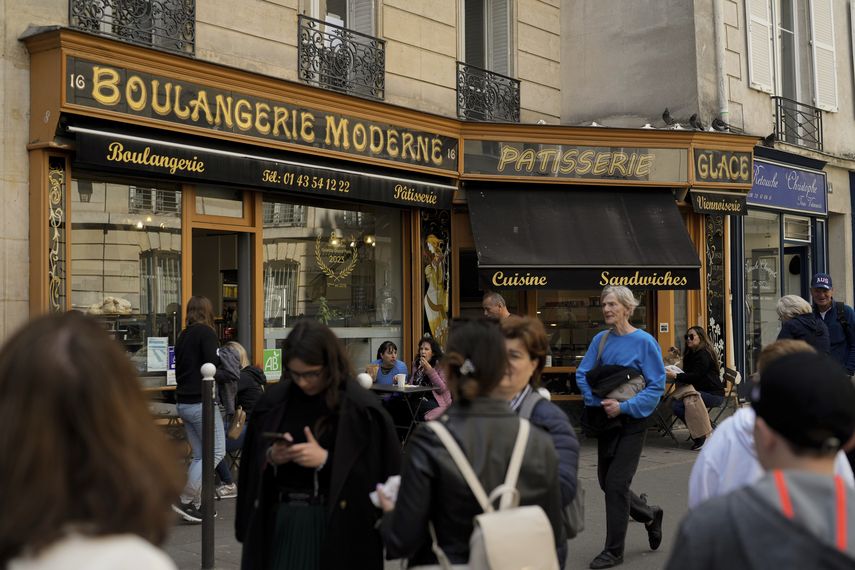 Gente camina frente a la Panadería Moderna en Place de dEstrapade, en París, el 19 de abril de 2023. El enorme éxito de la serie de Netflix Emily en Paris ha transformado una plaza tranquila de la capital francesa en un imán para turistas.