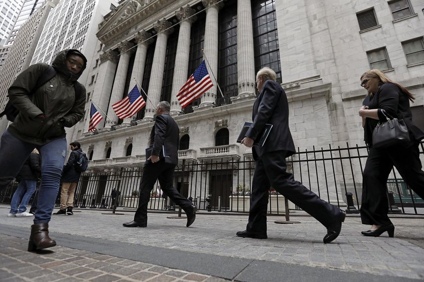 Varias personas caminan frente al edificio de la bolsa de valores Wall Street, en Nueva York.