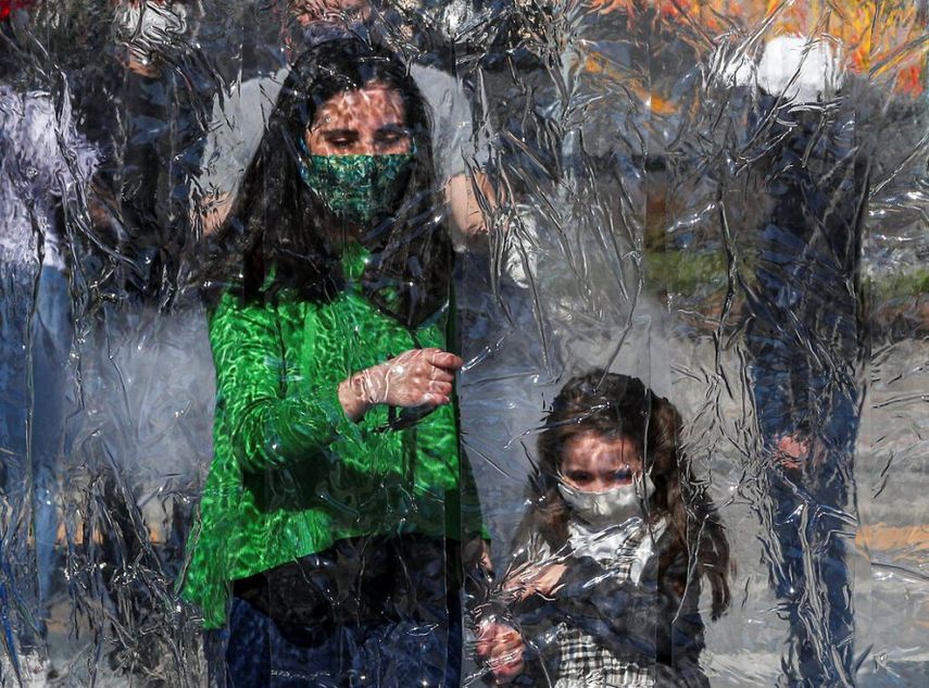 Una mujer y una niña con mascarilla entran a una sala de descontaminación como precaución contra la propagación del coronavirus, a la entrada de un parque en Santiago, Chile.  América Latina registra ya más de 200 mil muertes por el COVID-19.