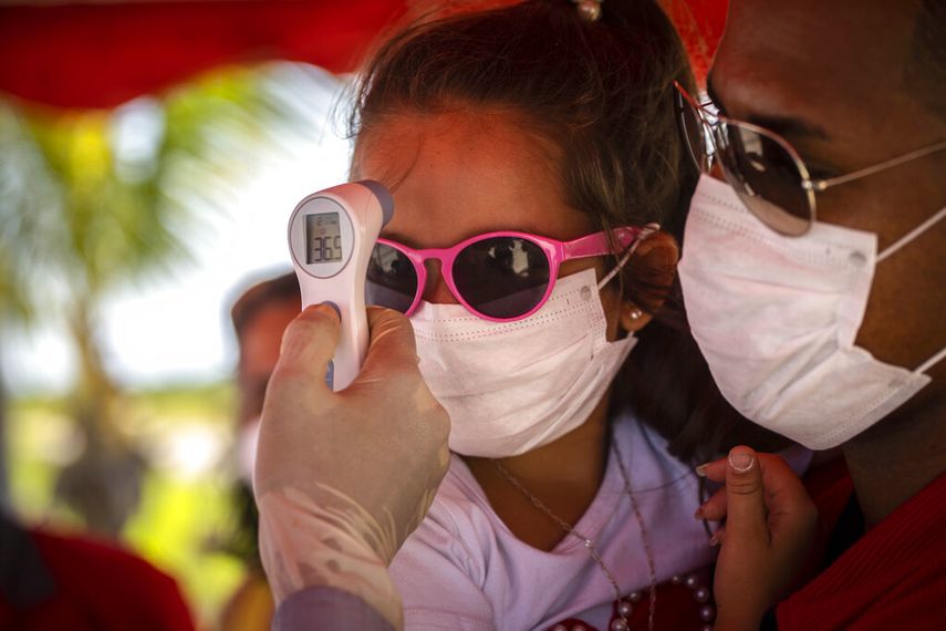 A una niña con mascarilla para protegerse del nuevo coronavirus le toman la temperatura en un puesto de control policial en la entrada de la provincia de La Habana, Cuba, el lunes 10 de agosto de 2020.&nbsp;