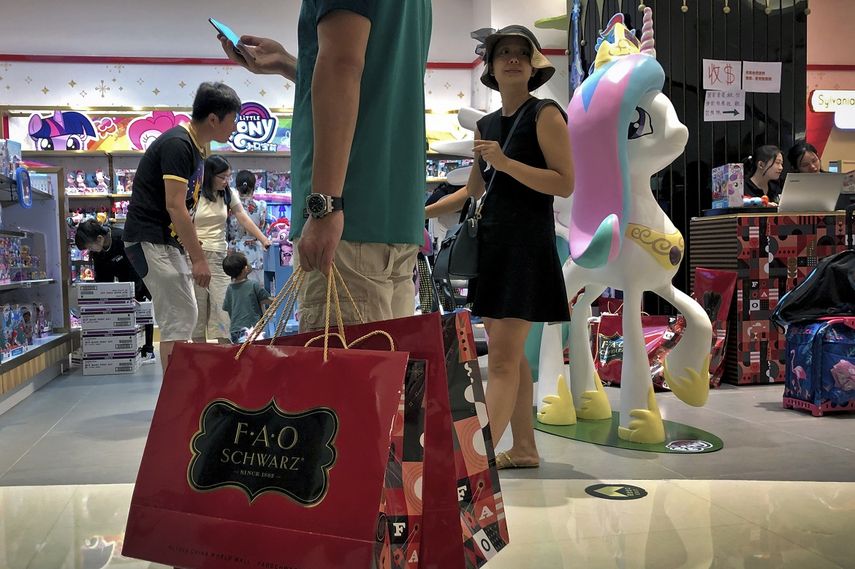 En esta imagen de archivo, tomada el 1 de junio de 2019, un hombre carga con bolsas de papel con juguetes adquiridos en FAO Schwarz, mientras otras personas compran en la tienda en un popular centro comercial en Beijing.&nbsp;