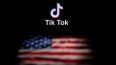 La foto muestra el logotipo de la aplicación de red social TikTok (arriba) y una bandera de Estados Unidos (abajo) en las pantallas de dos computadoras.