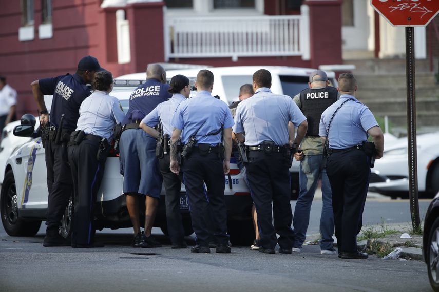 Varios policías de Filadelfia se resguardan detrás de un vehículo durante un tiroteo en el vecindario Nicetown de Filadelfia, el miércoles 14 de agosto de 2019.&nbsp;
