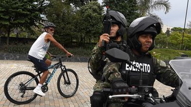 Un hombre pasa en bicicleta junto a soldados colombianos en motocicleta que patrullan en vísperas de las elecciones presidenciales en Medellín, Colombia, el 28 de mayo de 2026.