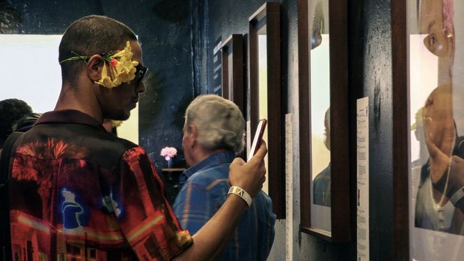 Un hombre toma una instantánea durante la exposición ¨Masculinidades¨ de la fotógrafa cubana Monik Molinet, en la Fabrica de Arte de La Habana, el 6 de abril de 2022.