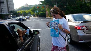 Una partidaria del candidato opositor a la presidencia Edmundo González muestra cómo votar por él durante un acto de campaña en Caracas.