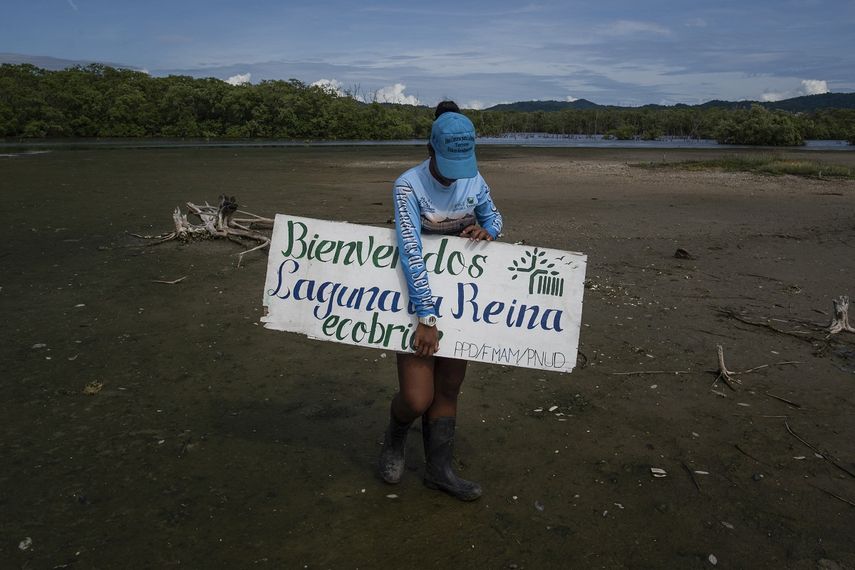 Un miembro de la fundación ecológica Ecobrion sostiene un cartel que dice Bienvenidos a la laguna La Reina en el humedal costero del sector Valle Seco en Higuerote, estado Miranda, Venezuela, el 4 de octubre de 2022.&nbsp;