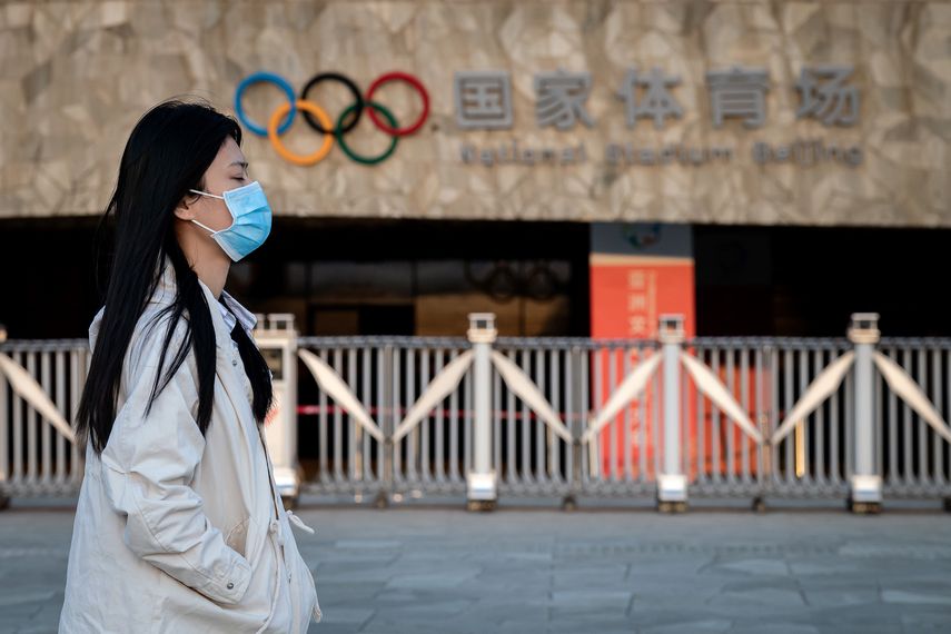 Una mujer que usa una m&aacute;scara facial como medida preventiva contra el nuevo coronavirus COVID-19 camina en el parque ol&iacute;mpico de Beijing el 23 de marzo de 2020.