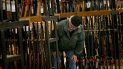 Un hombre viendo la sección de fusiles en una tienda.