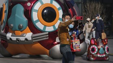 Una pareja con mascarilla para evitar contagios del coronavirus se hace una foto con un tigre robótico colocado como decoración en un centro comercial de Pekín, la víspera del Año Nuevo Lunar, el lunes 31 de enero de 2022.&nbsp;