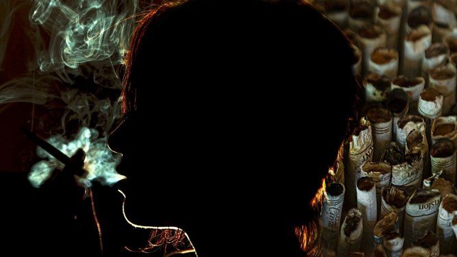 Una mujer exhala el humo del cigarillo por la boca.&nbsp;