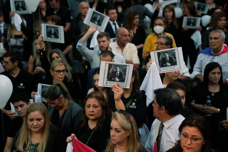 Personas sosteniendo una imagen del difunto fiscal antidrogas Marcelo Pecci asisten a una reunión para exigir justicia por su asesinato, en Asunción, Paraguay, el viernes 13 de mayo de 2022. 